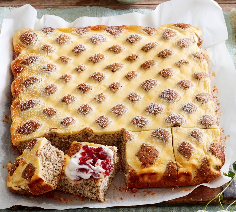 Steppdecken-Mohnkuchen, gebacken auf einem Blech und angeschnitten serviert mit Preiselbeer-Sahne und Puderzucker.  | © EAT CLUB / Isabell Triemer