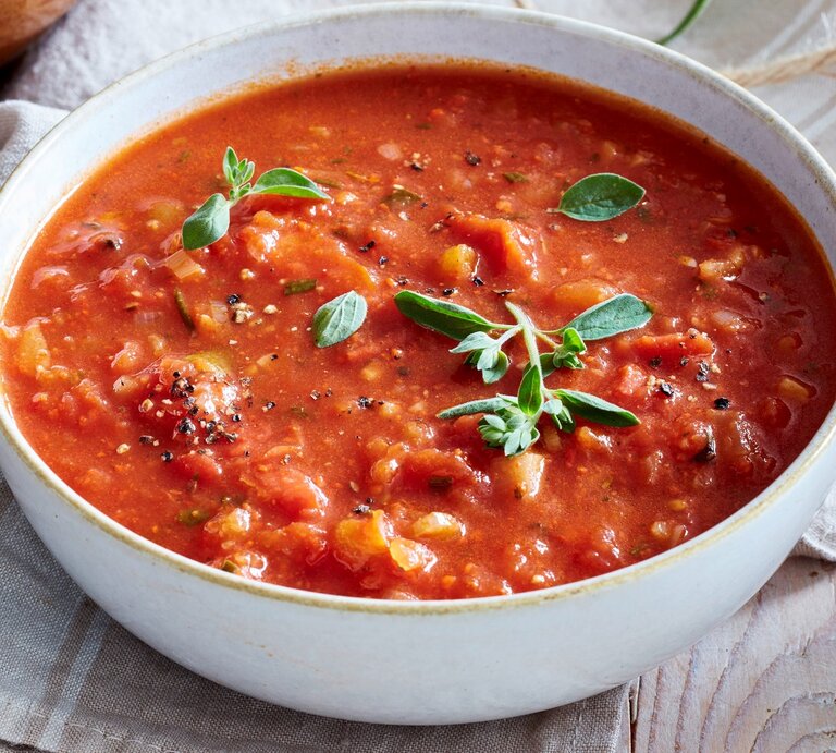 In einer Schüssel ist eine Portion feurige Tomatensuppe mit Rosmarin angerichtet. Sie ist mit Basilikum verfeinert. | © EAT CLUB / Isabell Triemer