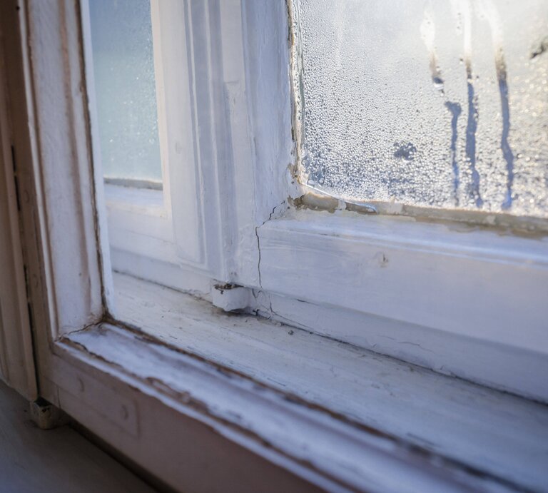 Close-up von einer Ecke der Fensterscheibe, in der sich Kondenswasser gebildet hat und die Scheibe hinunterläuft. | © imago images / photothek