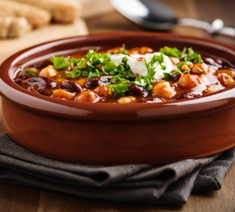Eine Schüssel Kichererbsen-Chili mit frischer Petersilie. | © Adobe Stock/ Martin Rettenberger