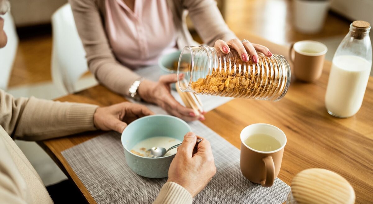 Eine Frau schüttet ihrem Mann am Frühstückstisch Cornflakes in eine Schale