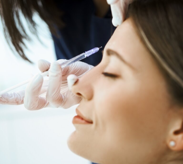 Frau bekommt eine Injektion im Rahmen einer Beauty-Behandlung | © Nastasic / GettyImages