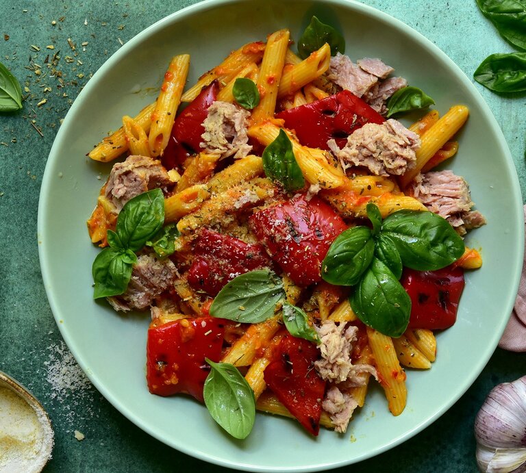 Ein grüner Teller mit der Penne an Thunfisch-Tomatensoße auf einem grünen Untergrund.  | © Shutterstock/ Liliya Kandrashevich