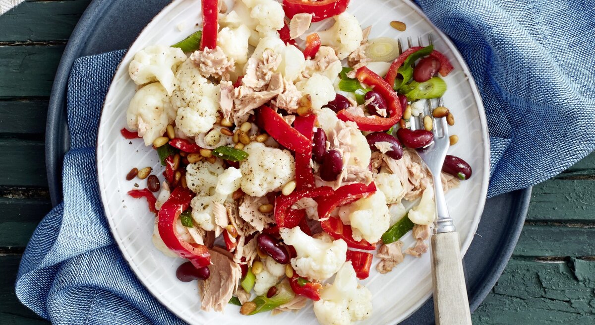 In einer Schüssel ist eine Blumenkohl-Thunfisch-Bowl angerichtet. Sie ist mit Bohnen und Paprika verfeinert.
