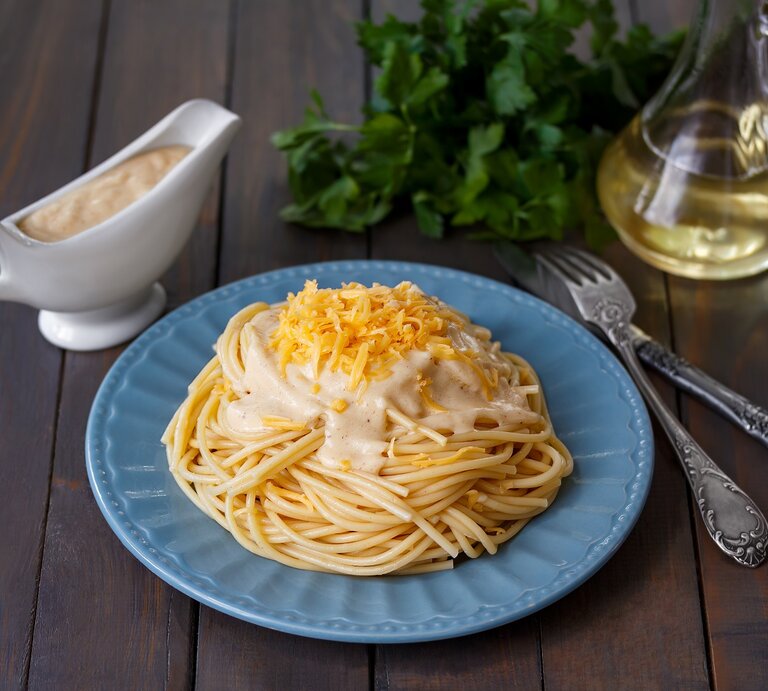 EIn Teller mit Pasta mit Schmelzkäse-Zitronensoße auf einem Holztisch. | © Shutterstock/Dementieva Iryna