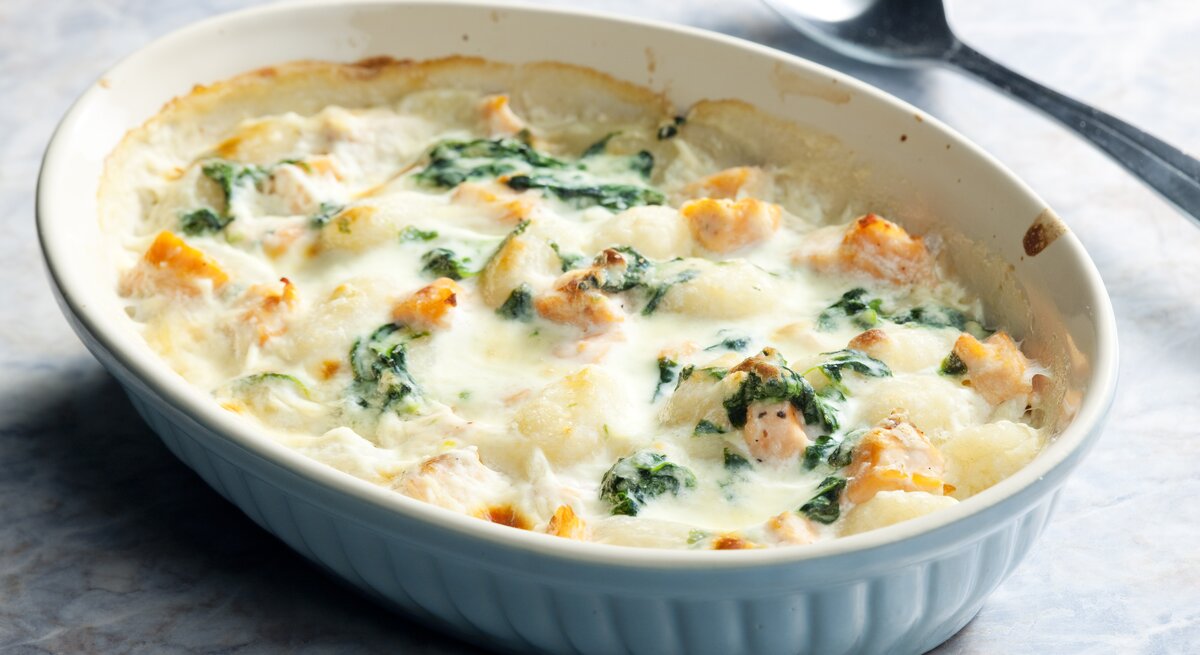 Gnocchi-Lachs-Auflauf mit Spinat in weißer Auflaufform. 