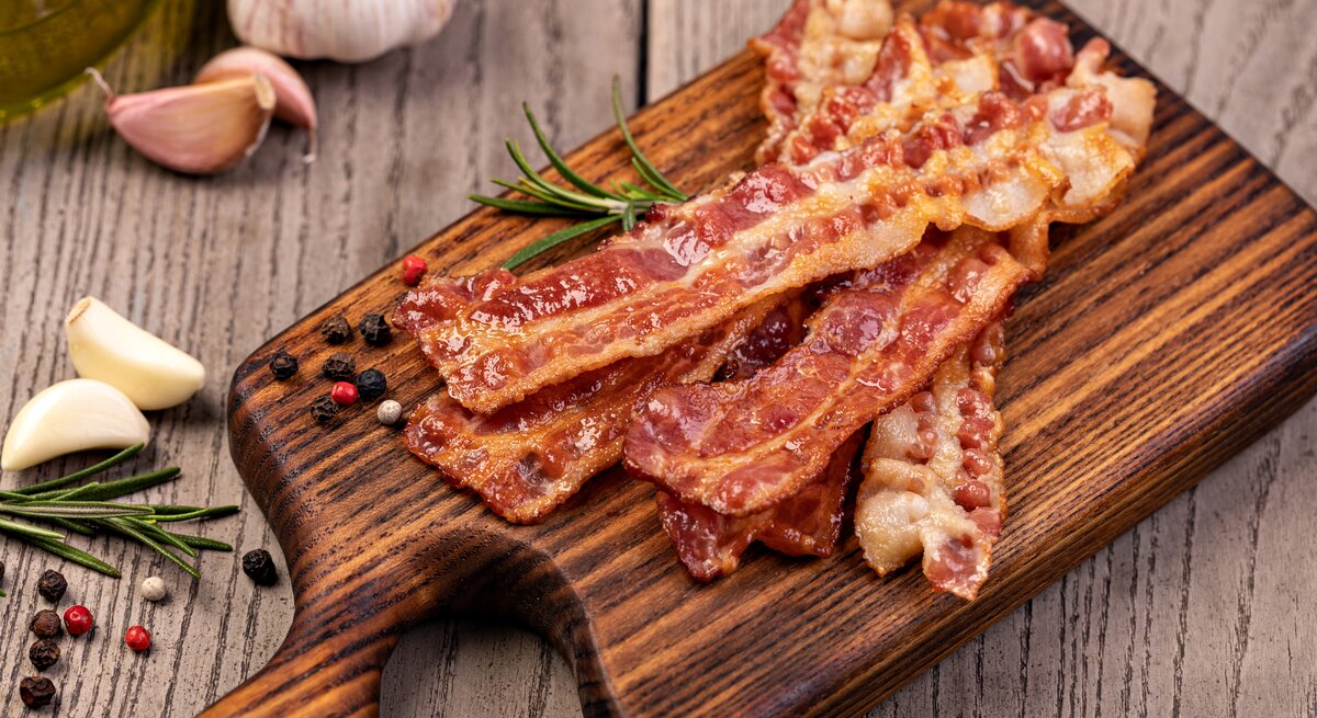 Knuspriger Bacon auf dem Holzbrett von oben fotografiert.