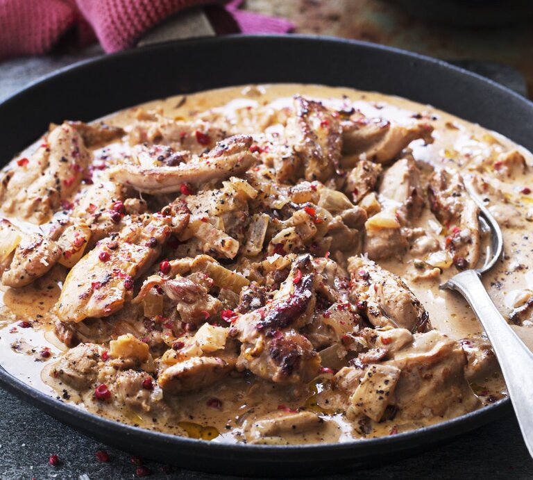 In einer tiefen Pfanne ist eine Portion Hühnereintopf mit Sahne und rosa Pfeffer angerichtet. Sie ist mit roten Pfeffer bestreut. | © StockFood / Hilden Smith, Eva