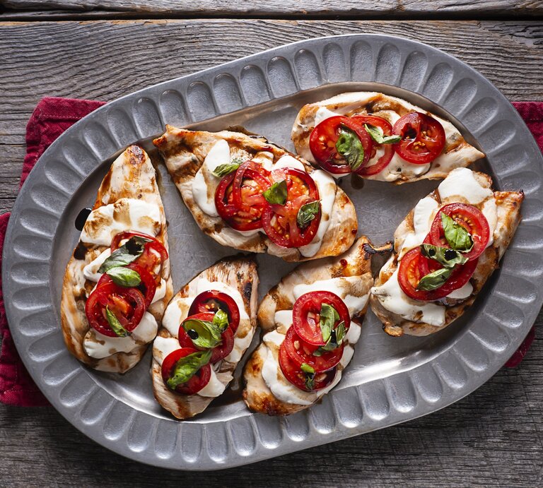 Hähnchen überbacken mit Tomate und Mozzarella auf Servierteller. | © Getty Images/rudisill