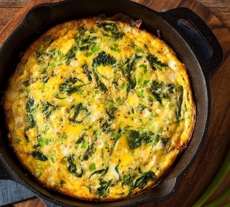Eine gusseiserne Pfanne mit der Frittata auf einem dunklem Holztisch. | © Shutterstock/ Brent Hofacker
