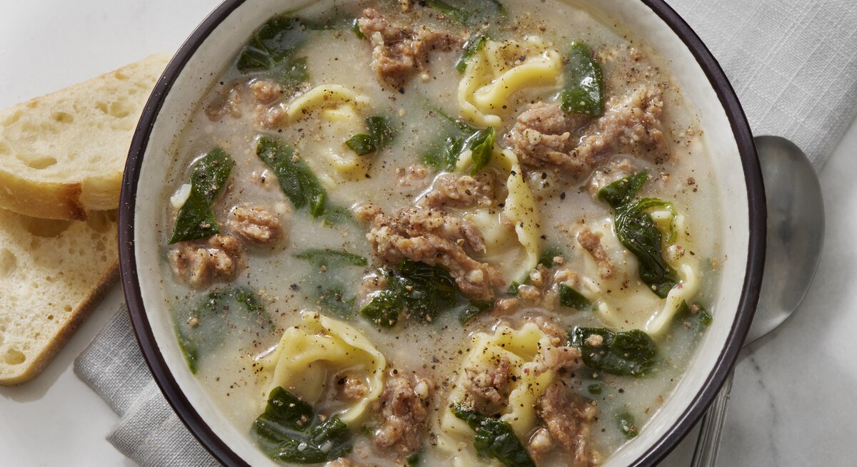 Suppenschüssel gefüllt mit einer cremigen Suppe mit Tortellini und Hackfleisch. 