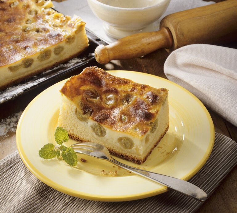 Ein gelber Teller mit einem Stück Schmandkuchen auf einem rustikalen Holztisch von schräg oben fotografiert. | © StockFood / Arras, Klaus