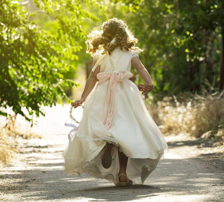 Ein Kind läuft in einem weißen Kleid einen Waldweg entlang | © IMAGO / Westend61