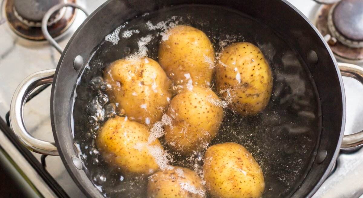Ein Kochtopf mit kochendem Wasser und Kartoffeln.