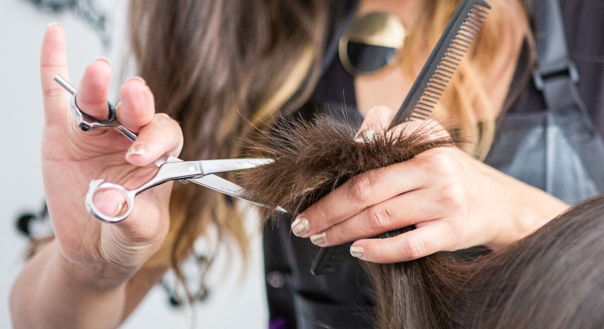 Frau lässt sich beim Friseur die Haare schneiden