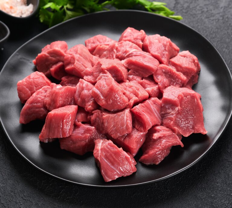 Ein schwarzer Teller mit dem Fleisch und einem grauen Hintergrund. Links neben dem Teller Gewürze und ein Bund Petersilie. | © Shutterstock/ Katarzyna Hurova