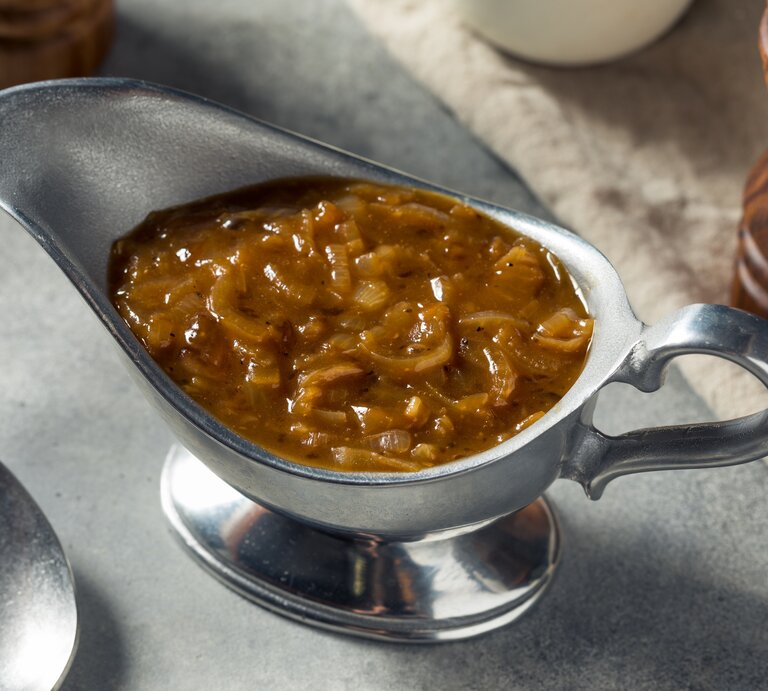 Braune Zwiebelsoße in einem Gefäß aus Edelstahl. | © GettyImages/bhofack2
