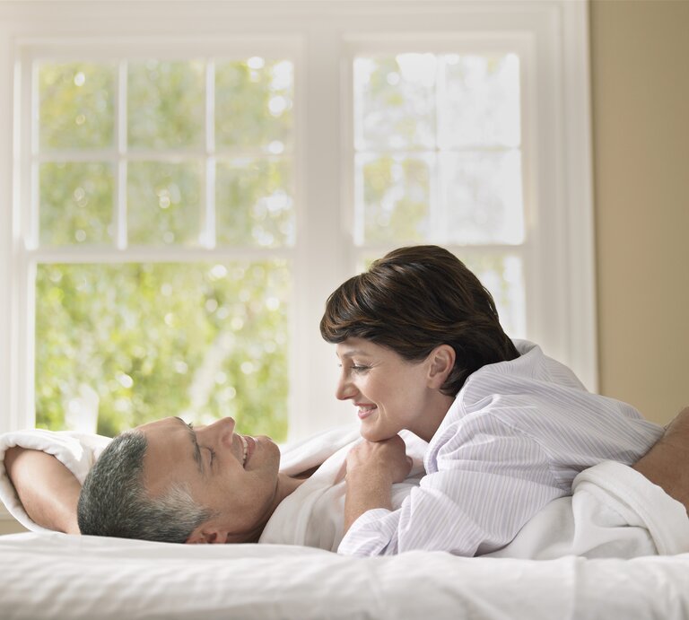 Frau und Mann lachend im Bett. | © iStock / IPGGutenbergUKLtd