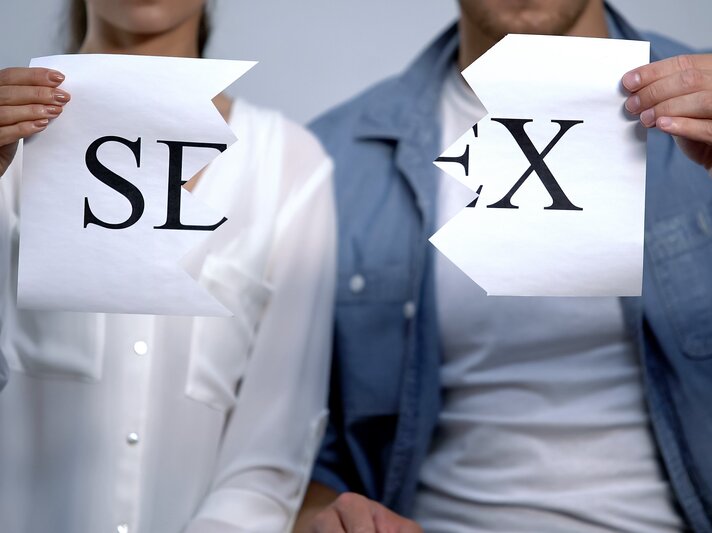 Paar, das jeweils eine Hälfte eines zerrissenen Blattes Papier hält. Auf den beiden Hälften steht zusammen das Wort "SEX". | © Getty Images / Motortion