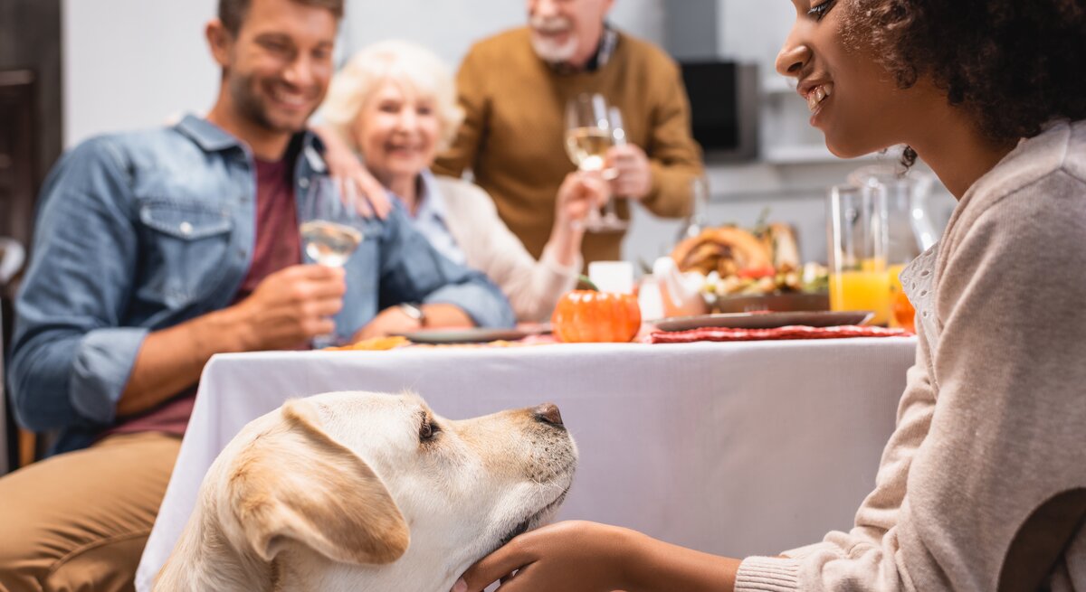 Familie sitzt am Tisch mit Hund.