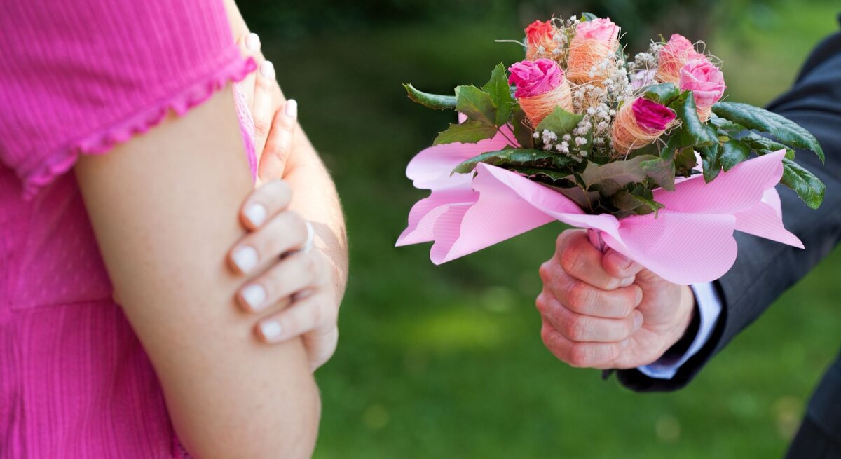 Mann überreicht Frau Blumenstrauß, von beiden Personen sind nur die Hände zu sehen