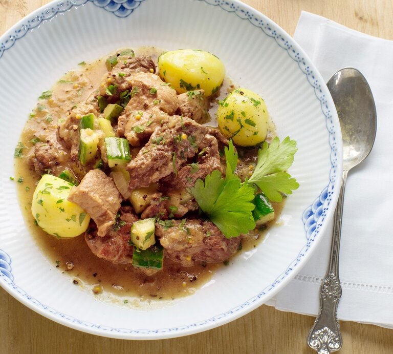 Auf einem Teller ist eine Portion sächsiches Senffleisch mit Schmorgurken angerichtet. Es ist mit Petersilie garniert. | © StockFood / StockFood Studios / Lehmann, Joerg