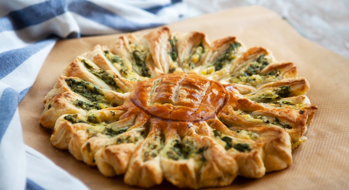 Zupfbrot-Sonne mit Spinat und Feta auf einem Holzbrett. 