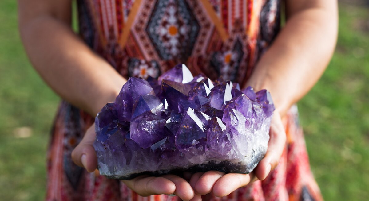 Eine Frau hält einen großen Amethyst in der Hand. 