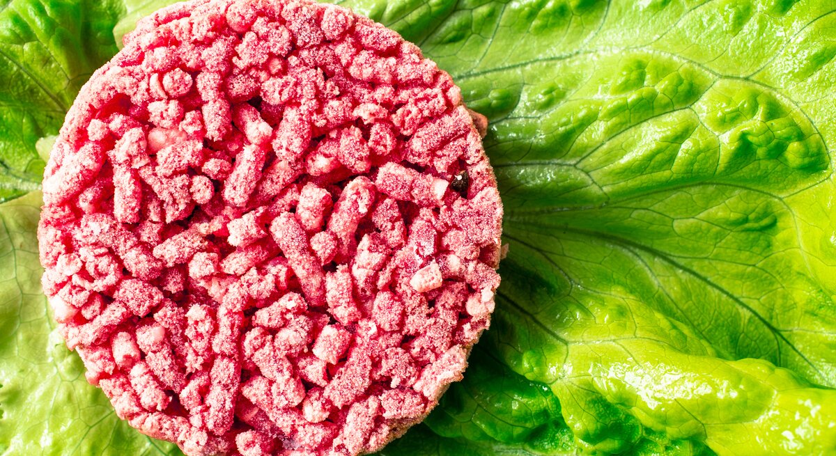 Ein gefrorener Hackfleisch-Burger-Patty auf Salat. 