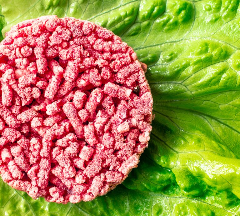Ein gefrorener Hackfleisch-Burger-Patty auf Salat.  | © iStock/Photosiber 