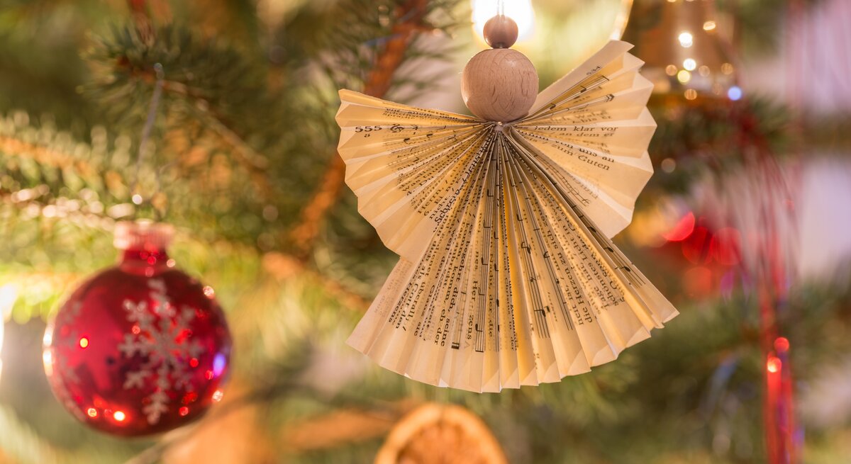Selbst gebastelter Engel aus Notenblättern hängt am Weihnachtsbaum.