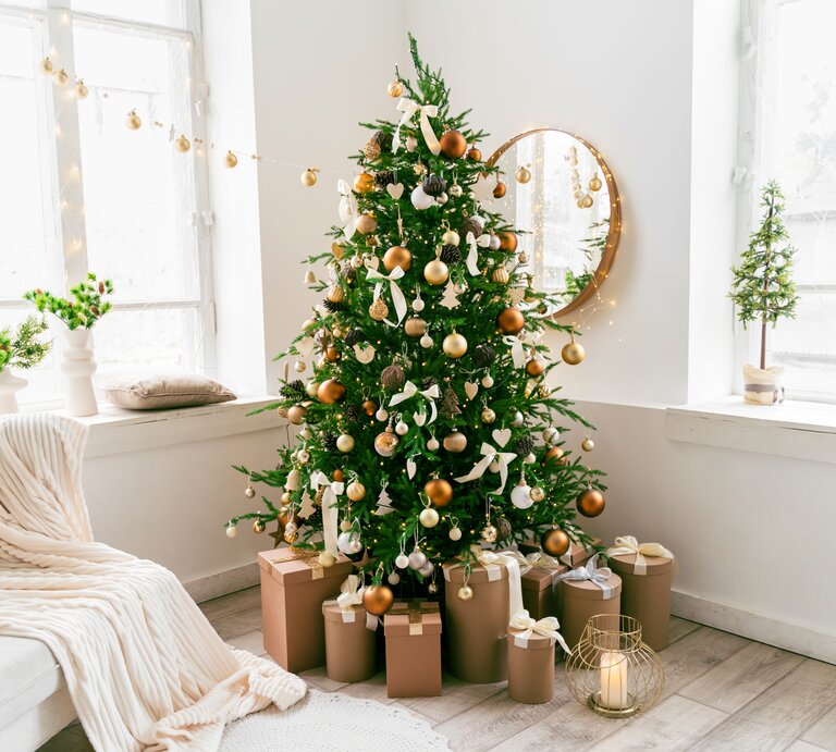 Weihnachtsbaum mit goldenen Kugeln steht im Wohnzimmer. Auch die andere Weihnachtsdeko ist in Gold gehalten.  | © GettyImages/ Yana Iskayeva