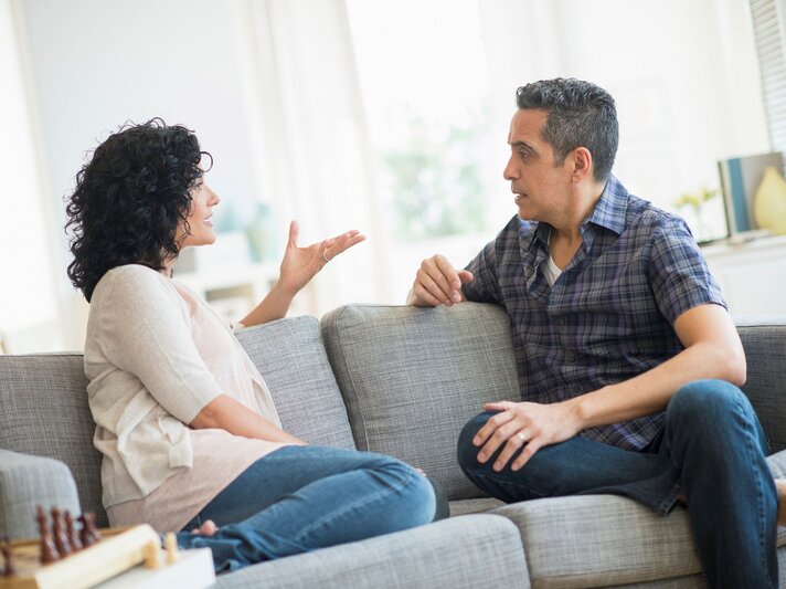 Paar sitzt auf dem Sofa und diskutiert | © Getty Images / Tetra Images
