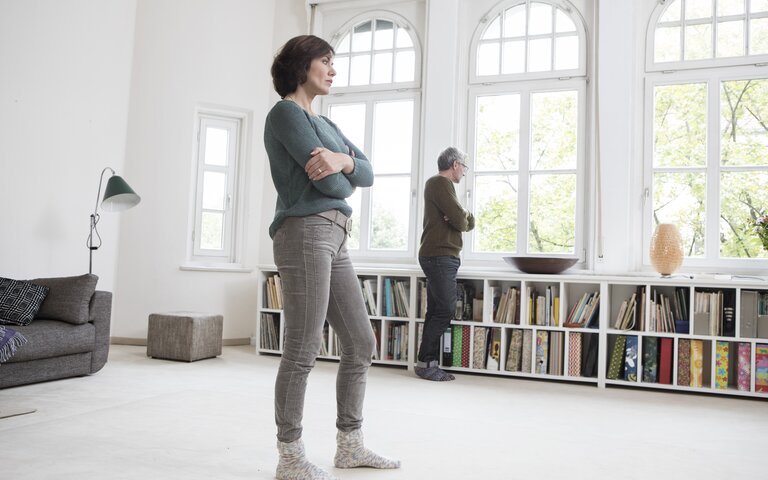 Paar schaut nachdenklich und mit Abstand aus dem Fenster | © Getty Images /	Westend61