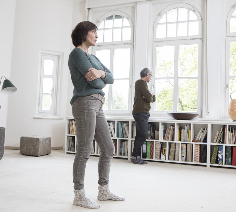 Paar schaut nachdenklich und mit Abstand aus dem Fenster | © Getty Images /	Westend61