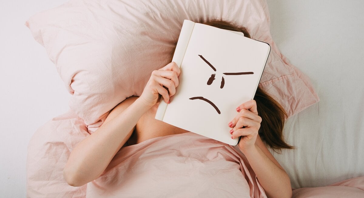 Frau im Bett mit schlechter Laune