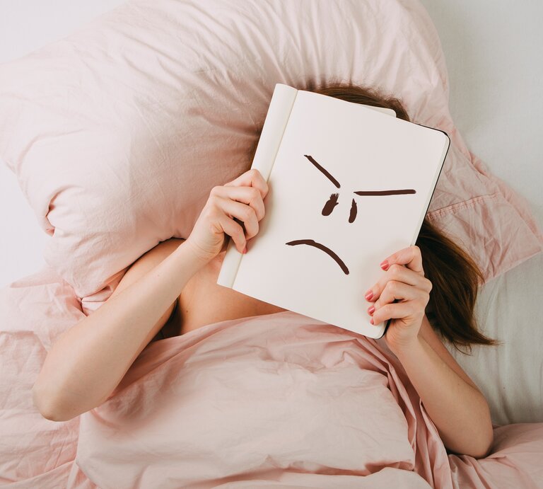 Frau im Bett mit schlechter Laune | © iStock/npdesignde