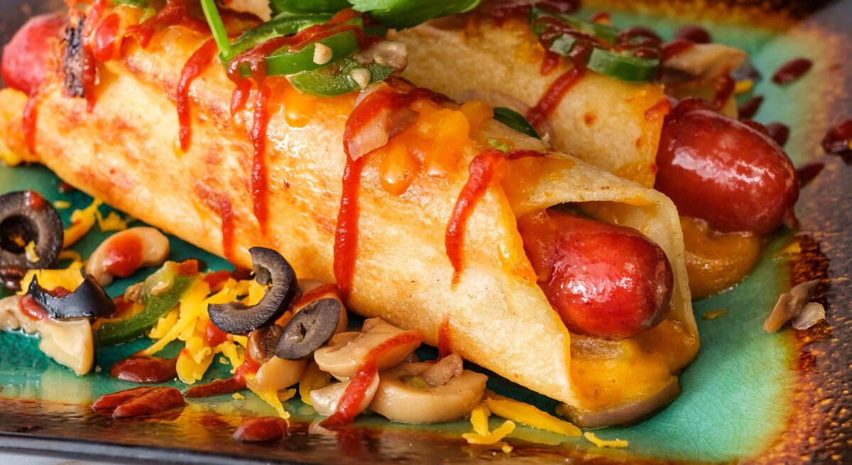 Low Carb Hot Dogs mit Toppings auf buntem Teller. Draufsicht.