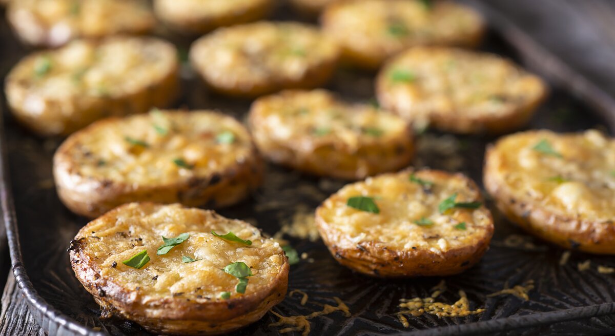 Parmesan-Kartoffeln auf einem Backblech, mit Käse überbacken.