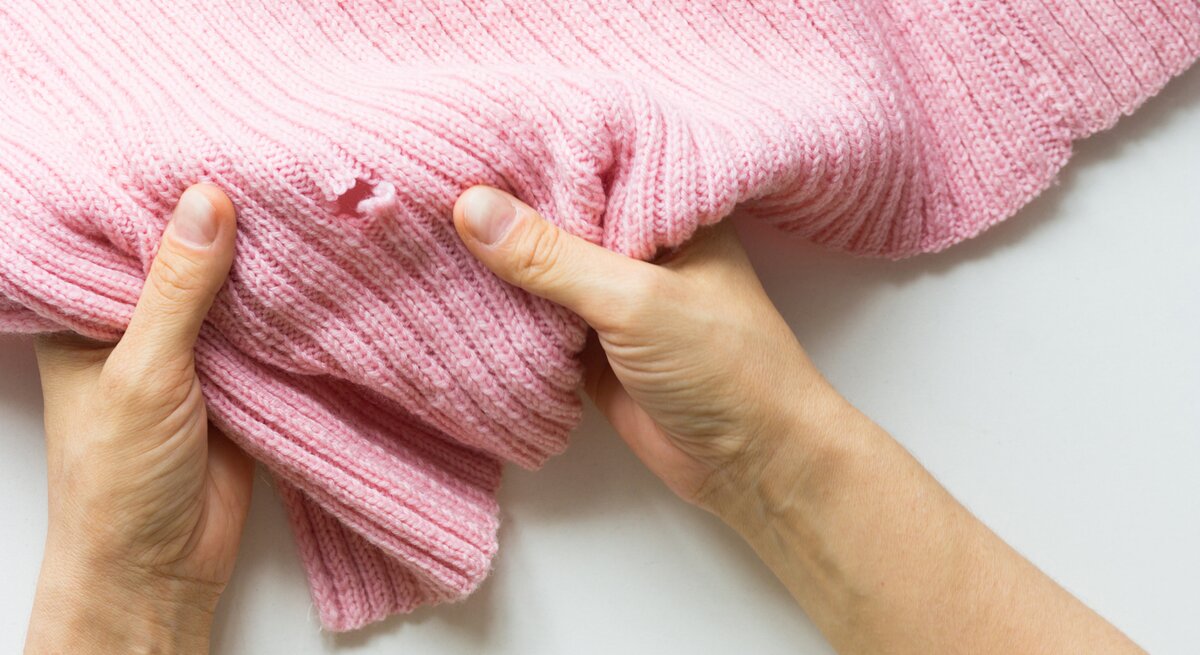 Ein rosa Pullover hat ein kleines Loch.