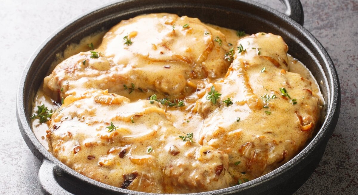 Schwarze gusseiserne Pfanne gefüllt mit Zwiebel-Sahne-Schnitzel.