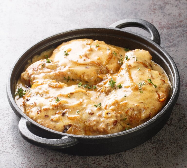 Schwarze gusseiserne Pfanne gefüllt mit Zwiebel-Sahne-Schnitzel. | © Getty Images/ALLEKO