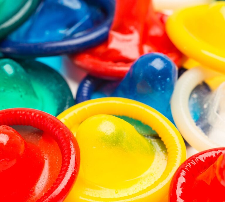 Nahaufnahme mehrerer Kondome in verschiedenen Farben wie Rot, Gelb, Grün und Blau. Sie sind in einer unregelmäßigen Anordnung auf einem Haufen platziert. | © Shutterstock / wavebreakmedia