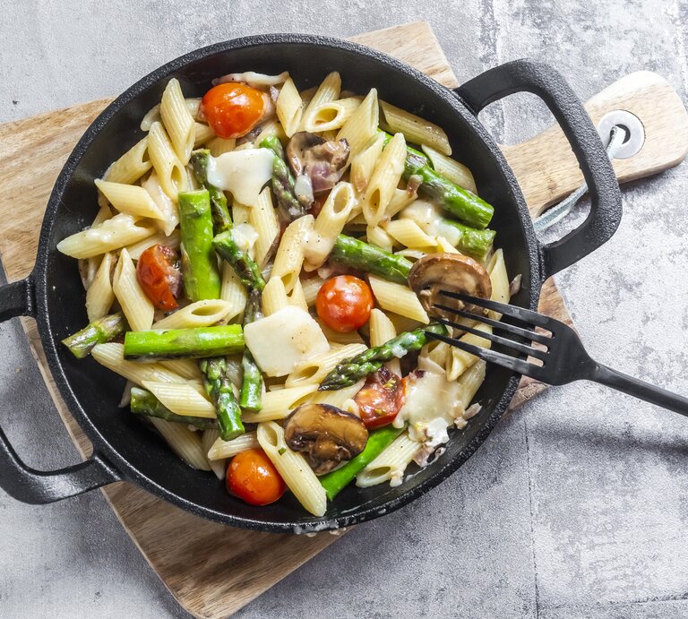 Spargel-Pasta-Pfanne mit Parmesan & Pilzen auf Holzbrett. | © Getty Images/Westend61