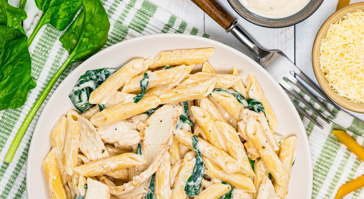 Pasta mit Parmesan-Spinat-Creme auf Teller angerichtet.