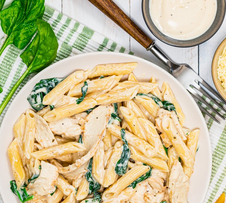 Pasta mit Parmesan-Spinat-Creme auf Teller angerichtet. | © Getty Images/ 	alisafarov
