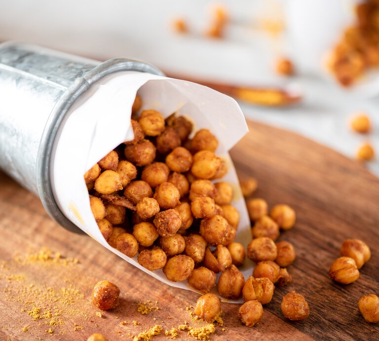 Eine Blechdose mit gerösteten Kichererbsen auf einem Holzbrett. | © Shutterstock/Svetlana Monyakova