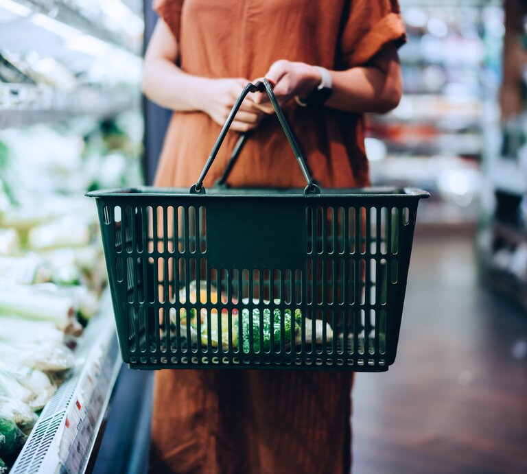 Vegan Food Award 2021: Eine Frau im Supermarkt hält einen Einkaufskorb und steht neben einem Gemüseregal. | © Getty Images/ d3sign