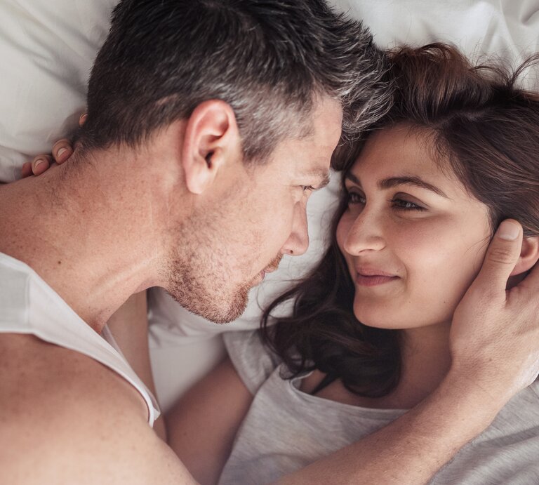 Ein Pärchen im Bett, das sich tief in die Augen schaut.  | © iStock/Jacob Ammentorp Lund