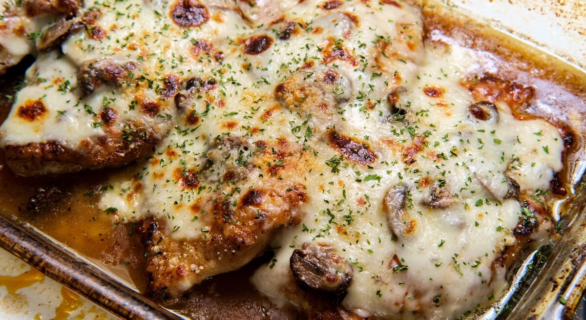Eine Auflaufform mit Hähnchen und überbackenem Käse in der Draufsicht.
